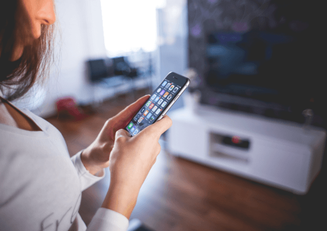 Femme avec un téléphone portable pour contrôler sa maison